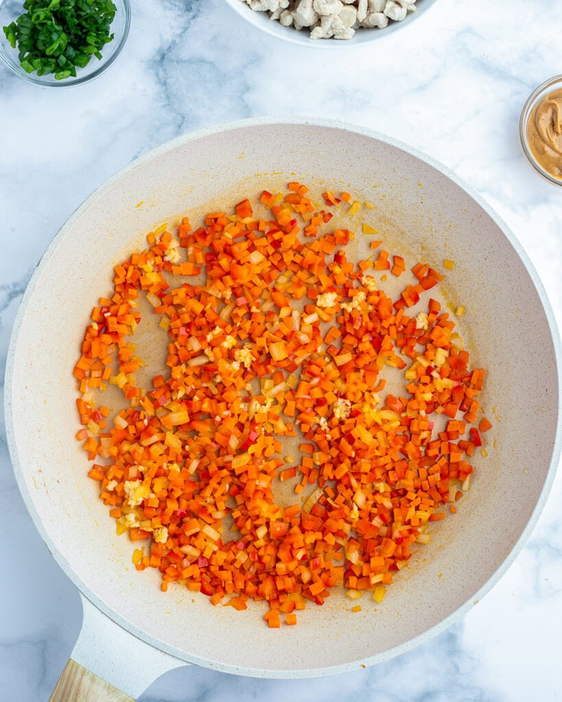 Cooked bell pepper and carrots in a skillet.