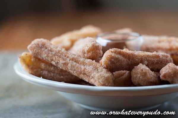 Close up view of churros stacked on a plate.