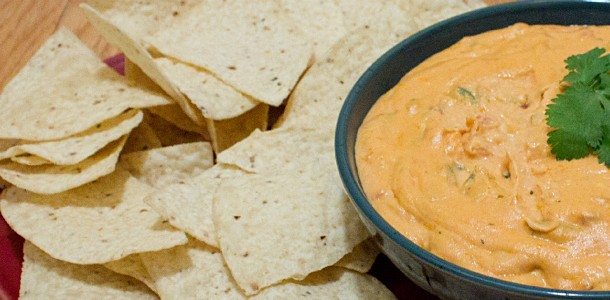 Close up view of a bowl of chips and nacho cheese in a bowl.