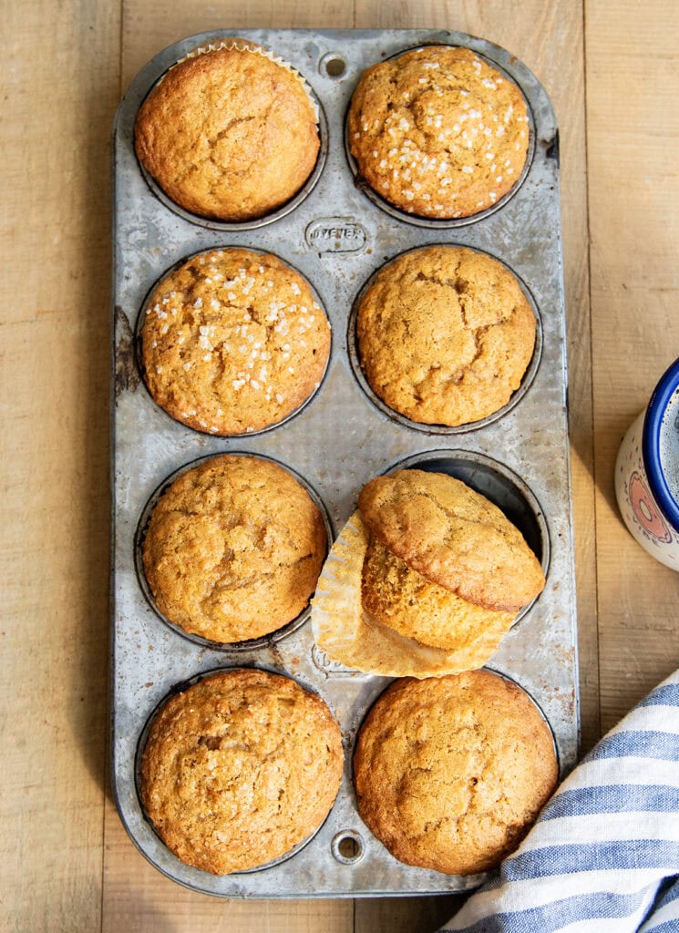 An above view of carrot muffins in a muffin pan. One muffin is sitting on its side.