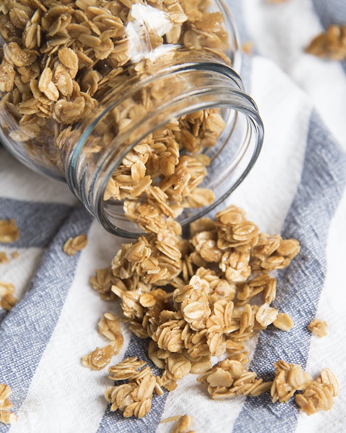 A mason jar knocked on its side with granola spilling out.
