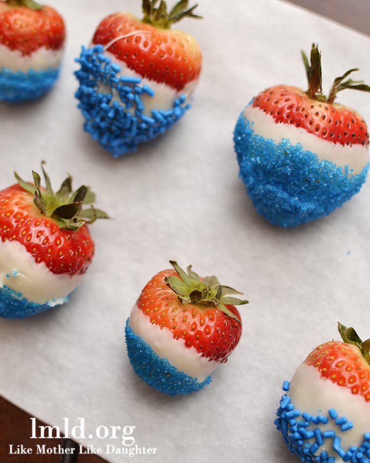 Red, white, and blue strawberries displayed dipped in white chocolate and blue sprinkles.