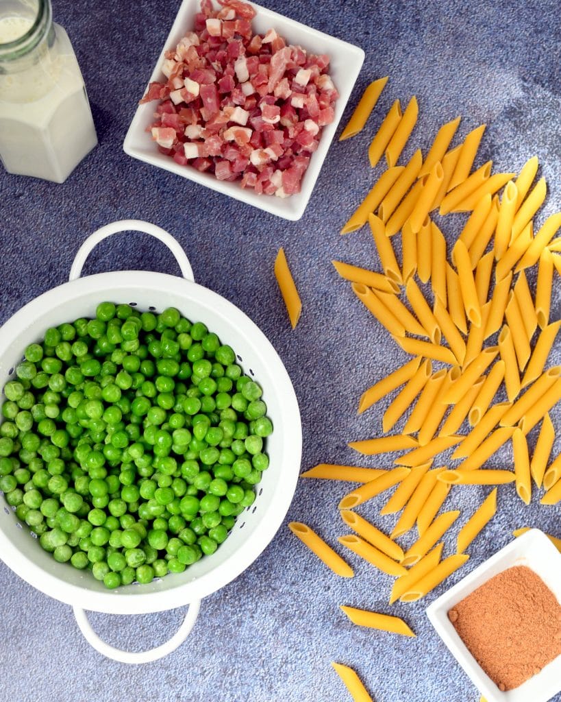 cream, ham, penne pasta, green peas, and nutmeg on a blue blackground