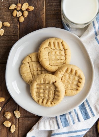 An overhead photo of peanut butter cookies with fork lines on the top on a white plate.