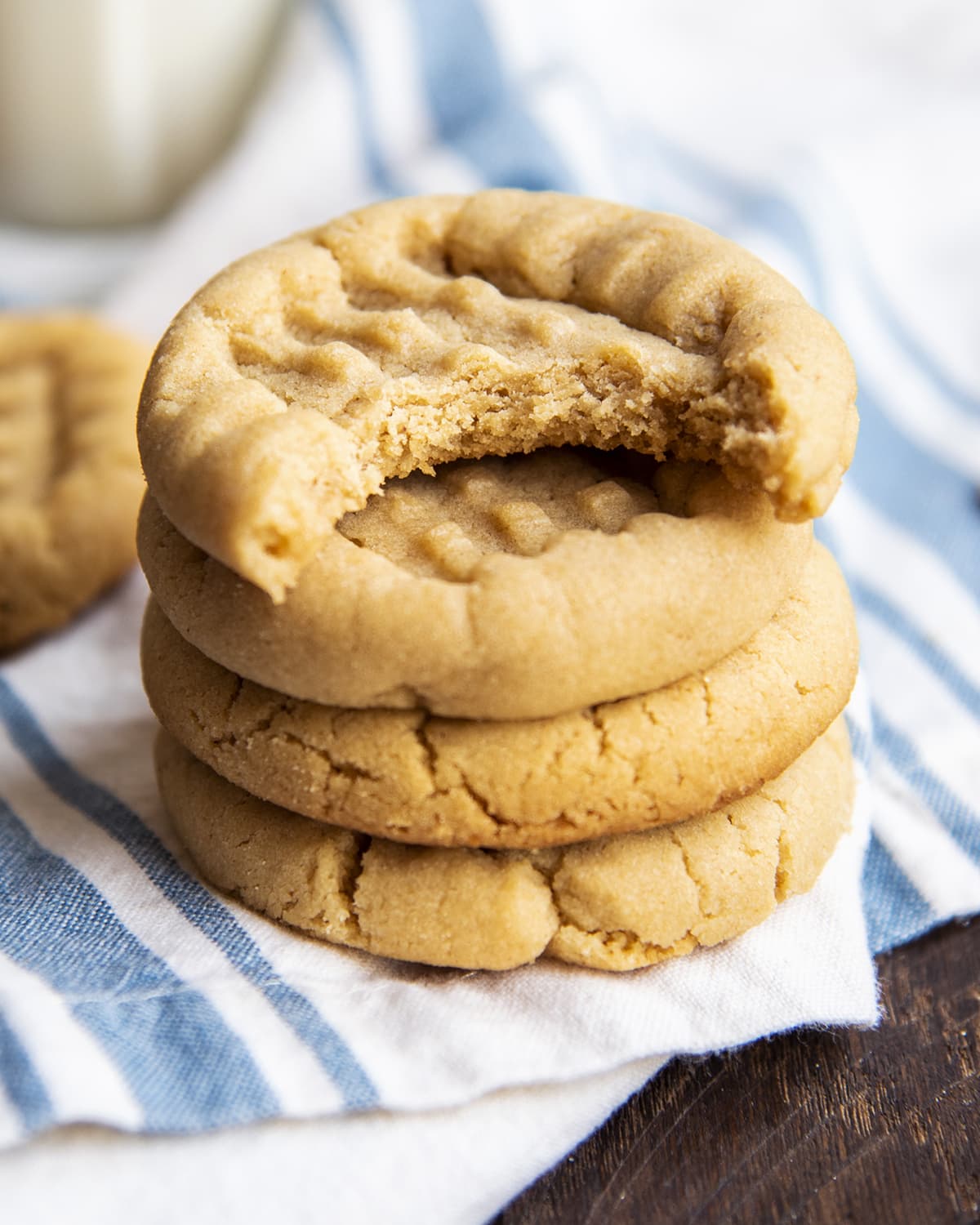 A stack of peanut butter cookies and the top cookie has a bite out of it.
