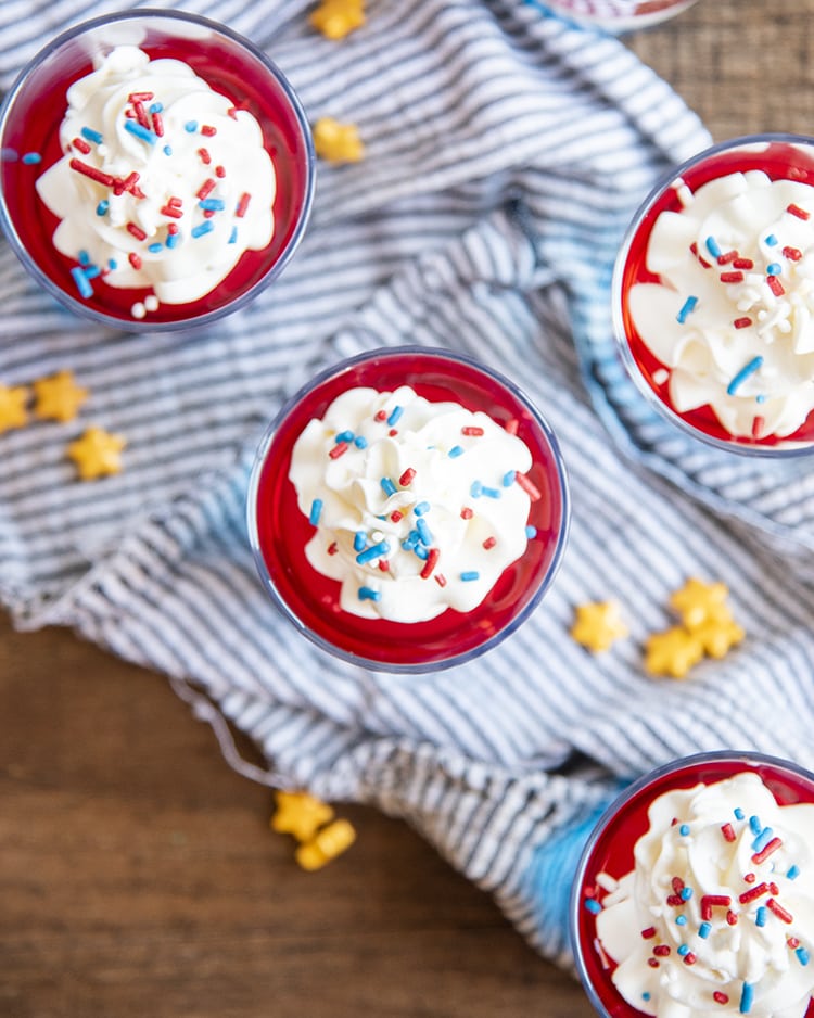 An overhead shot of jello in cups showing red jello topped with whipped cream