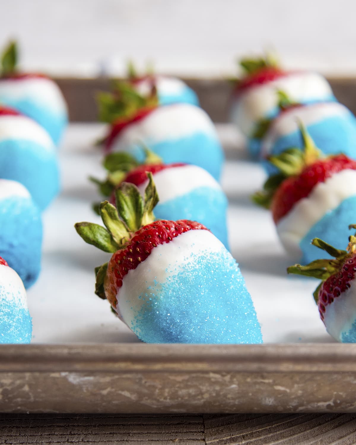 Rows of strawberries dipped in white chocolate, and blue sparkling sugar.