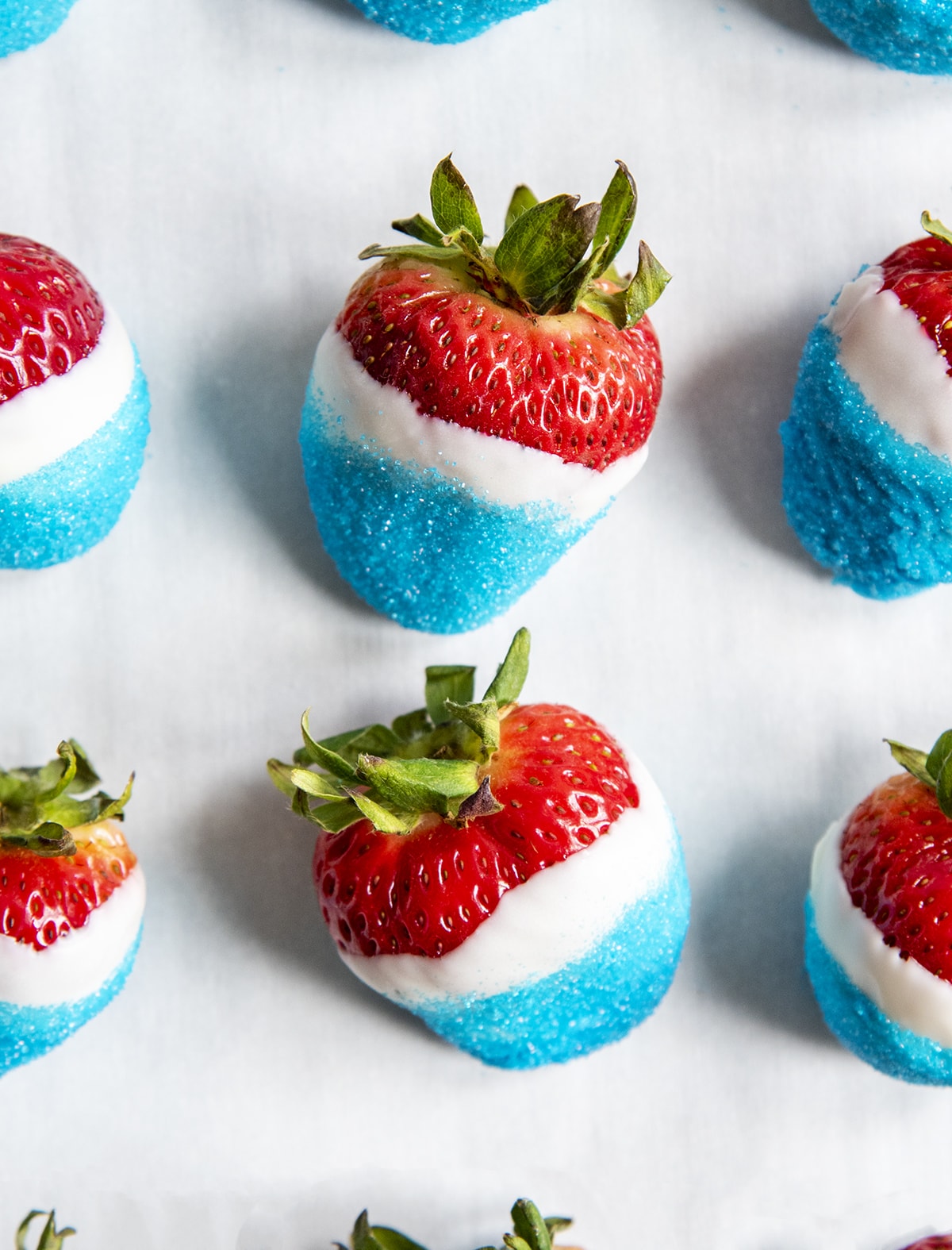 Red White and Blue covered strawberries on a piece of white waxed paper.