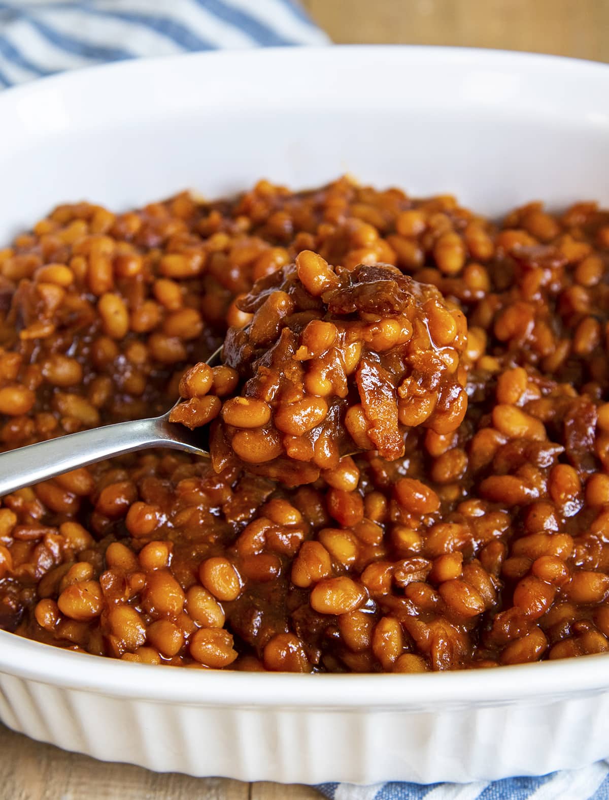 A spoonful of barbecue baked beans above a dish.
