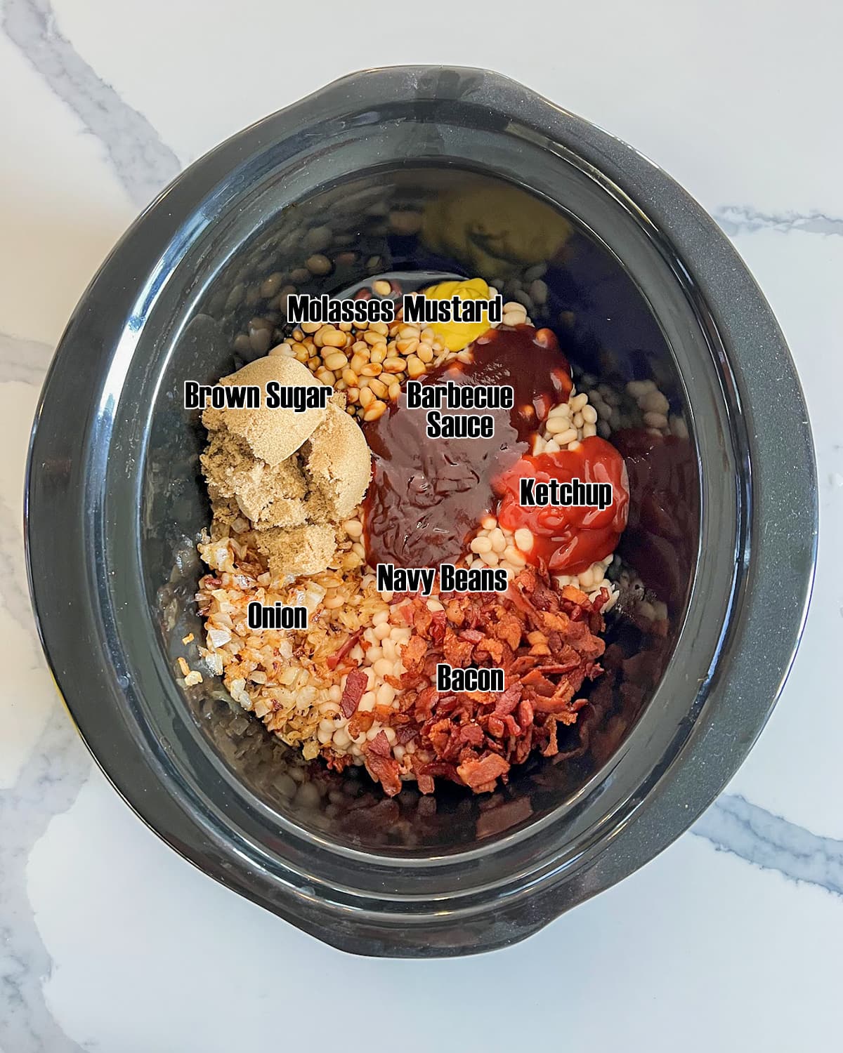 A slow cooker full of the ingredients needed to make slow cooker baked beans with text labels over them.