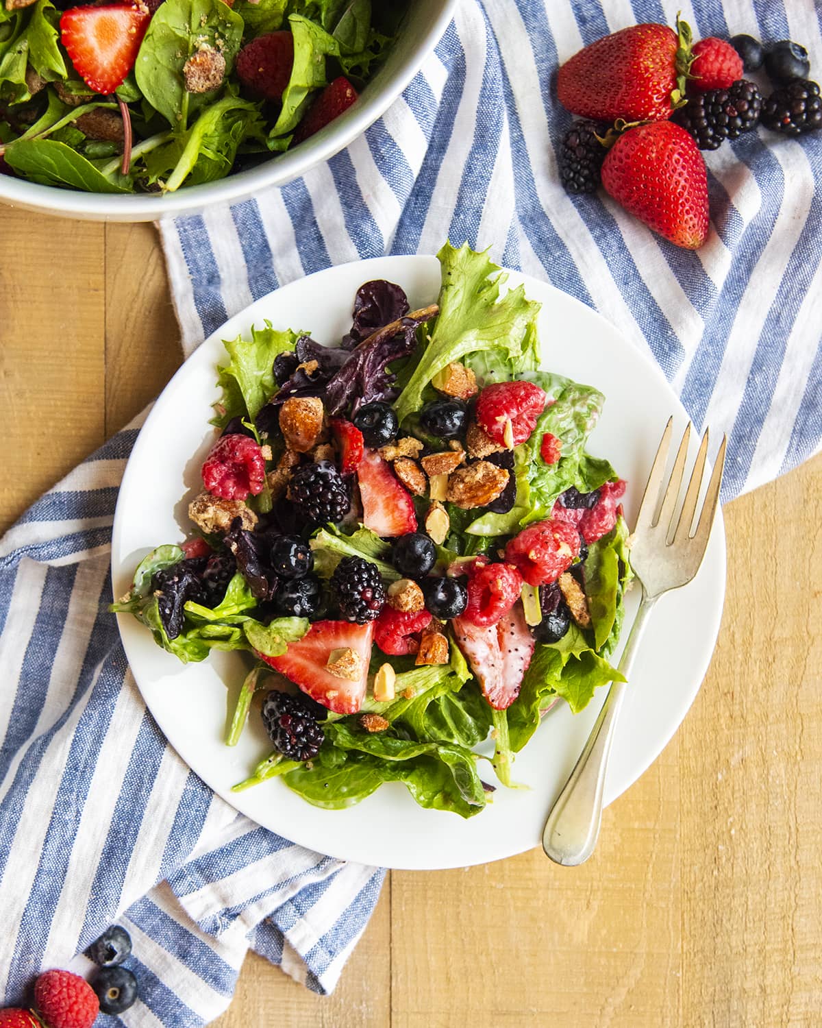 An overhead photo of a nuts about berries salad on a white plate with a fork.