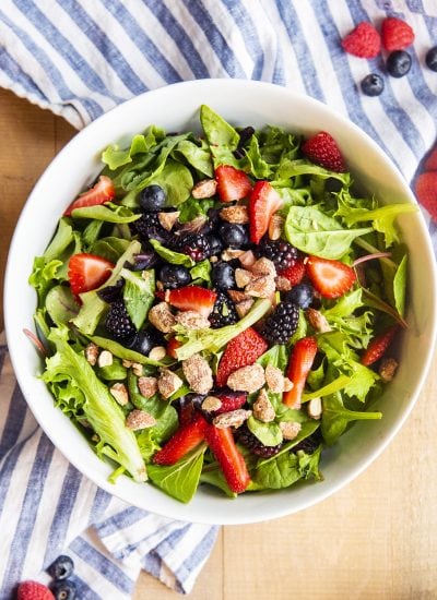 A salad with berries and candied almonds tossed together in a bowl with no dressing.