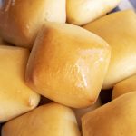 A close up of a basked of square style dinner rolls.