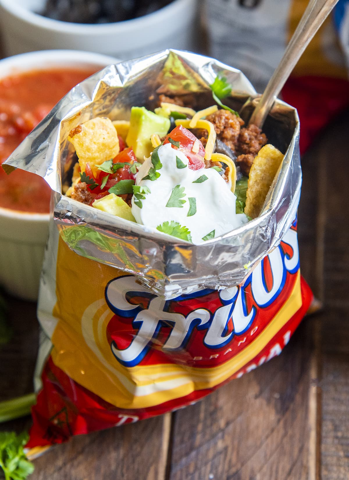 A walking taco in a frito bag with a fork in the bag.