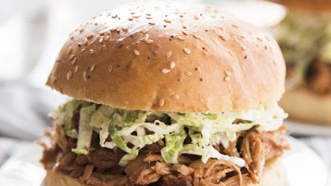 A bbq pork sandwich topped with coleslaw on a plate.