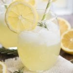 A glass of rosemary lemonade topped with fresh rosemary.