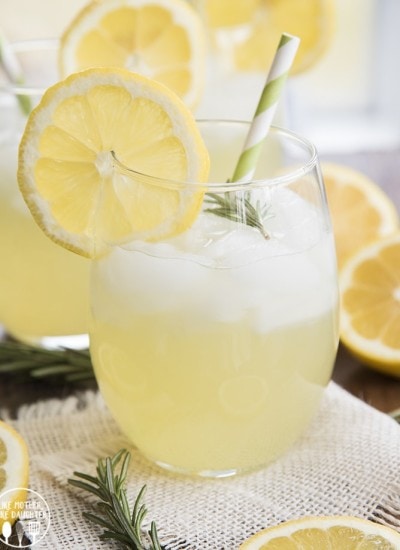 A glass of rosemary lemonade topped with fresh rosemary.