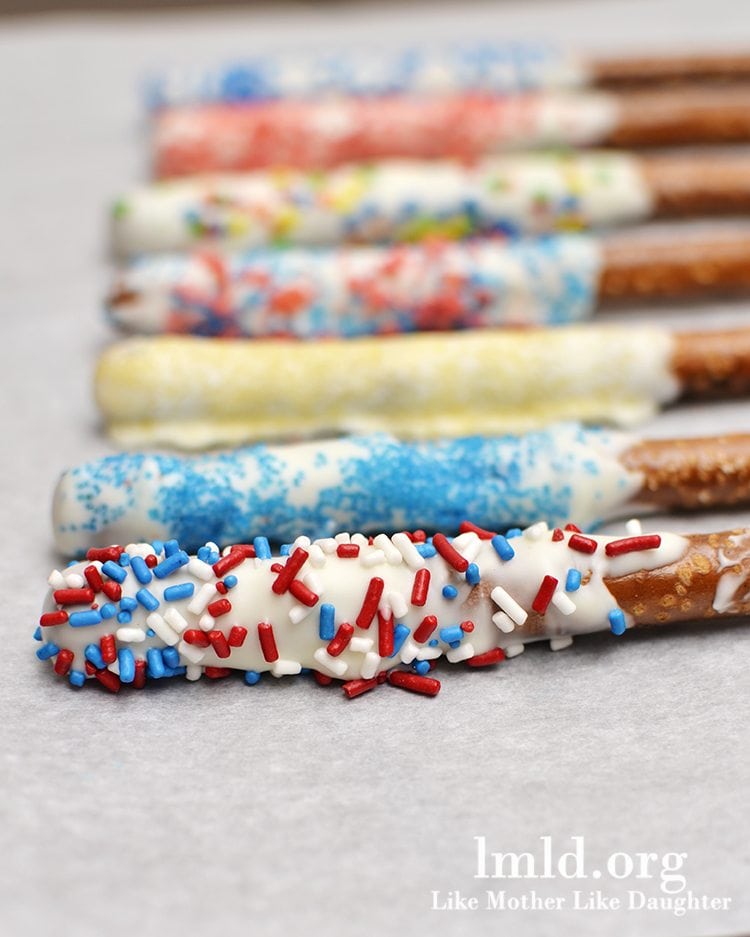Close up image of pretzel sparklers dipped in white chocolate and a variety of sprinkles.