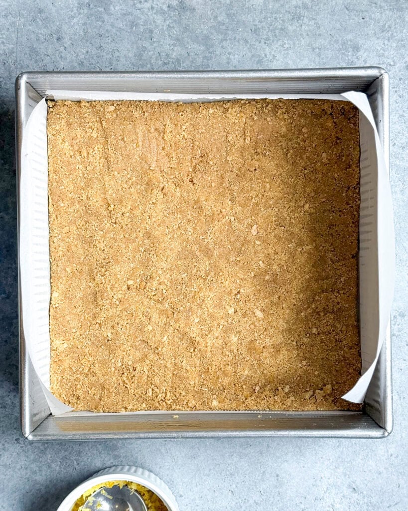 Graham cracker crust in a square pan.