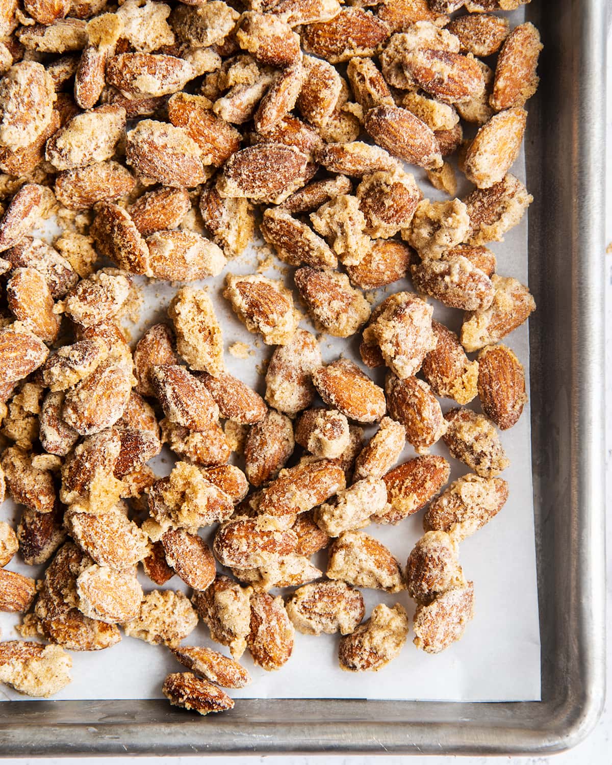 An overhead photo of cinnamon sugar candied almonds on a baking pan.