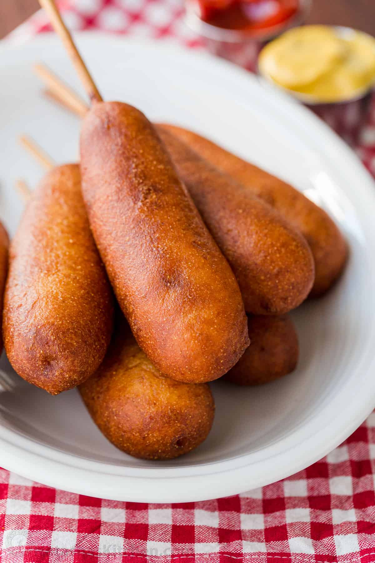 A pile of corn dogs on a white plate.