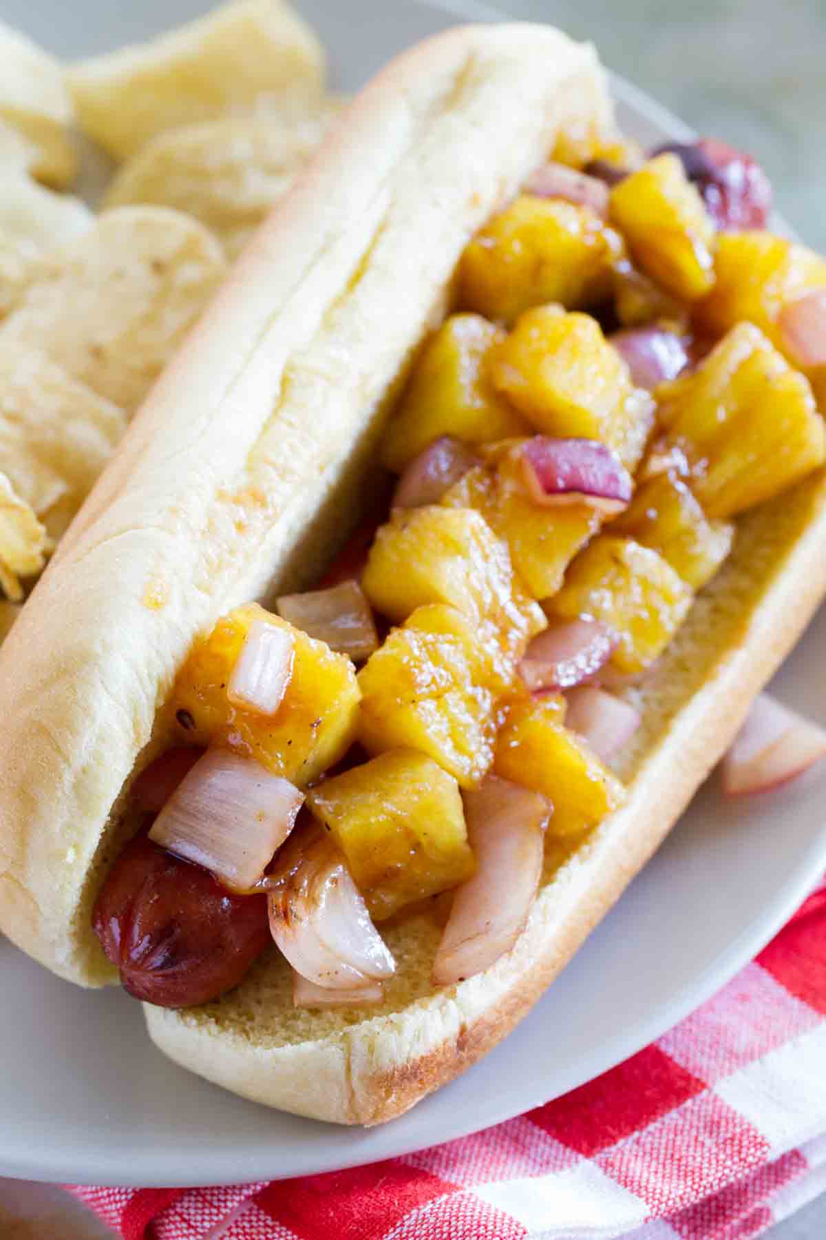 A hot dog topped with pineapple and onions.