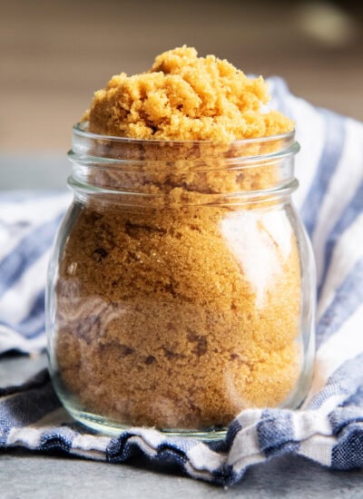 A glass jar full of brown sugar, and losely piling over the top.