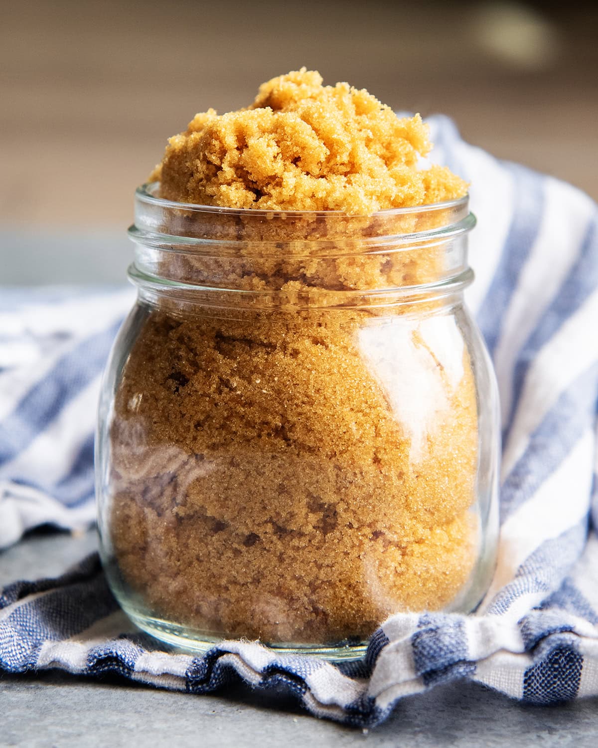 A glass jar full of brown sugar, and losely piling over the top.