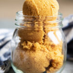 A jar full of brown sugar with a big tight packed scoop over the top.