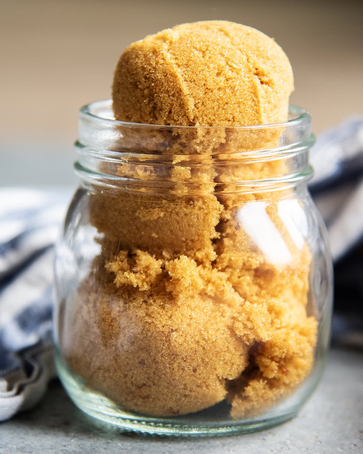 A jar full of brown sugar with a big tight packed scoop over the top.