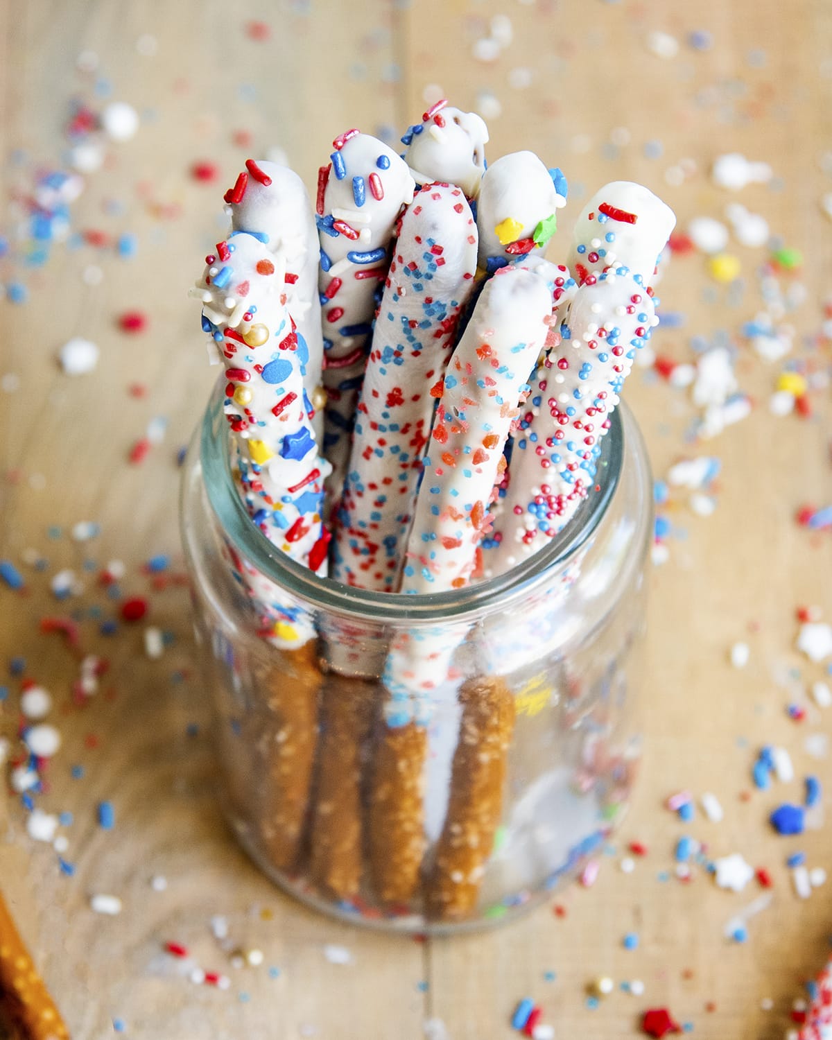 White chocolate dipped pretzel rods in a glass jar.