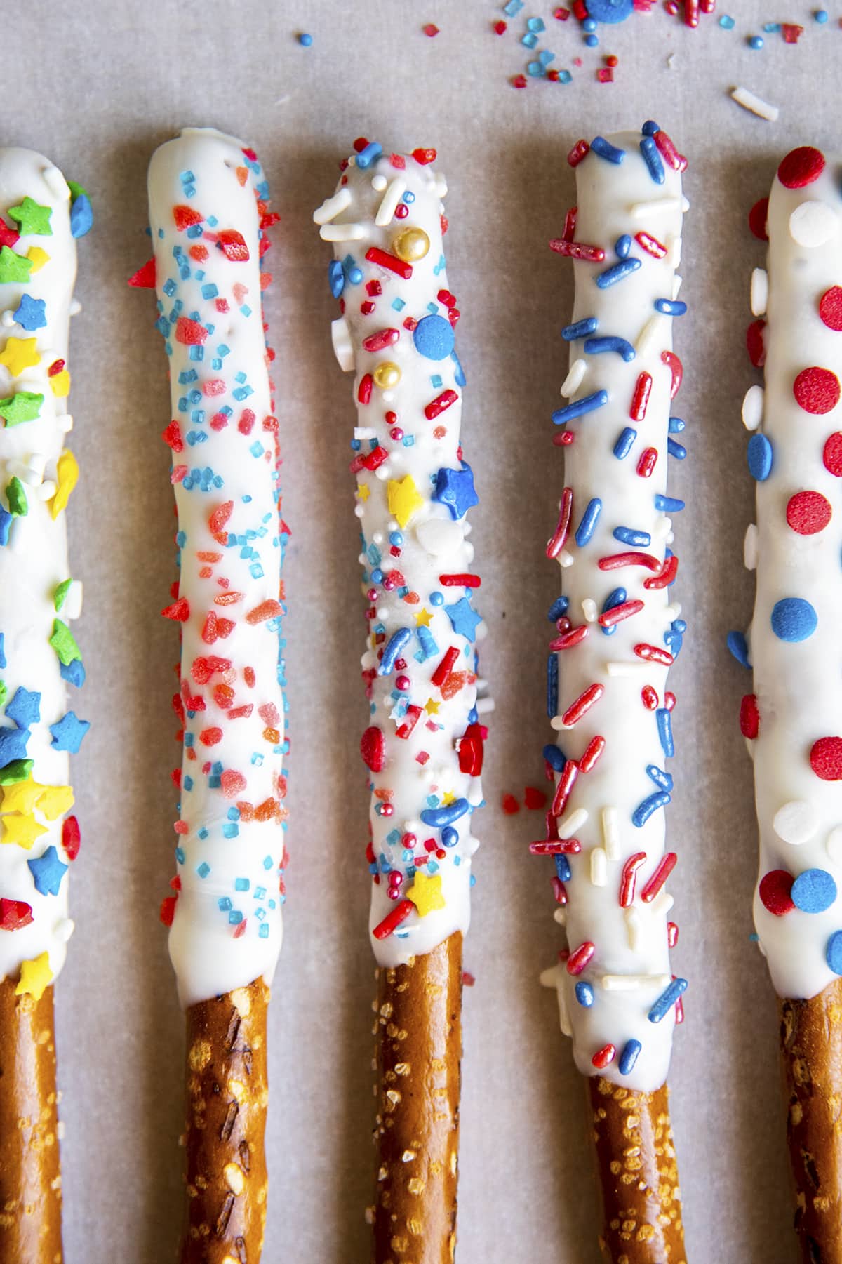 Five white chocolate covered pretzel sticks topped with Fourth of July sprinkles.