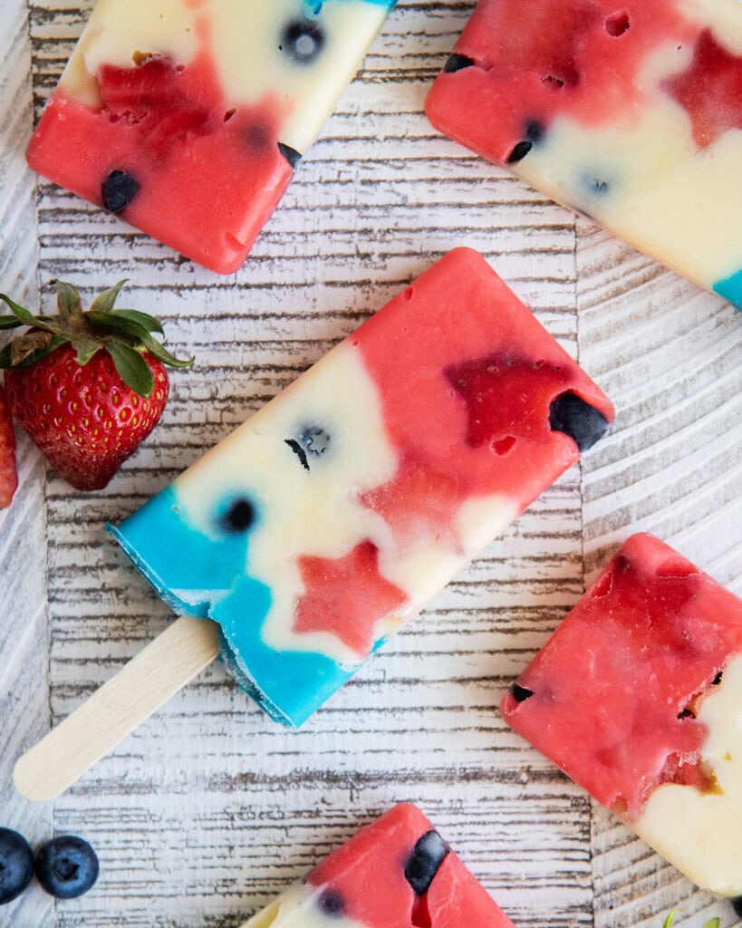 A popsicle on a wooden stick that is colored red, white, and blue. 