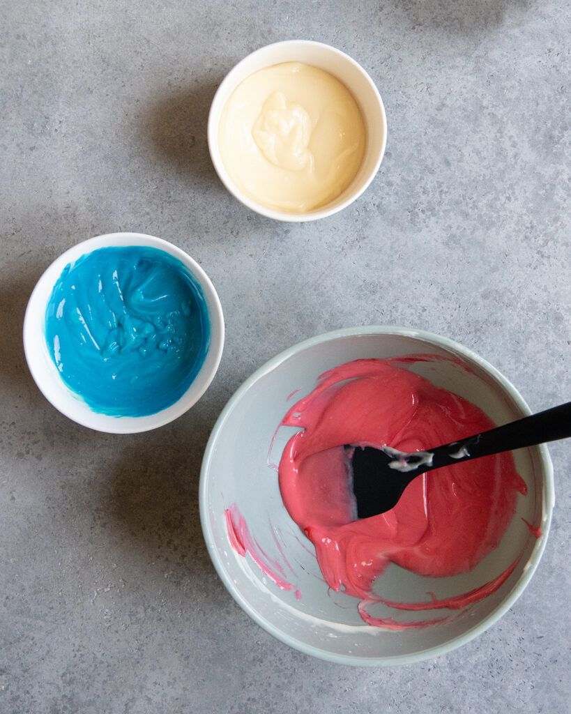 Three bowls of pudding, one is colored blue, and one is colored red.