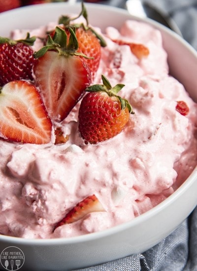 A close up of a bowl of strawberry fluff topped with fresh strawberries.