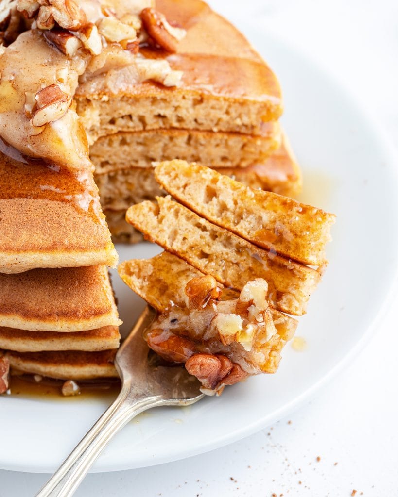 A forkful of pancakes in front of a stack of pancakes.