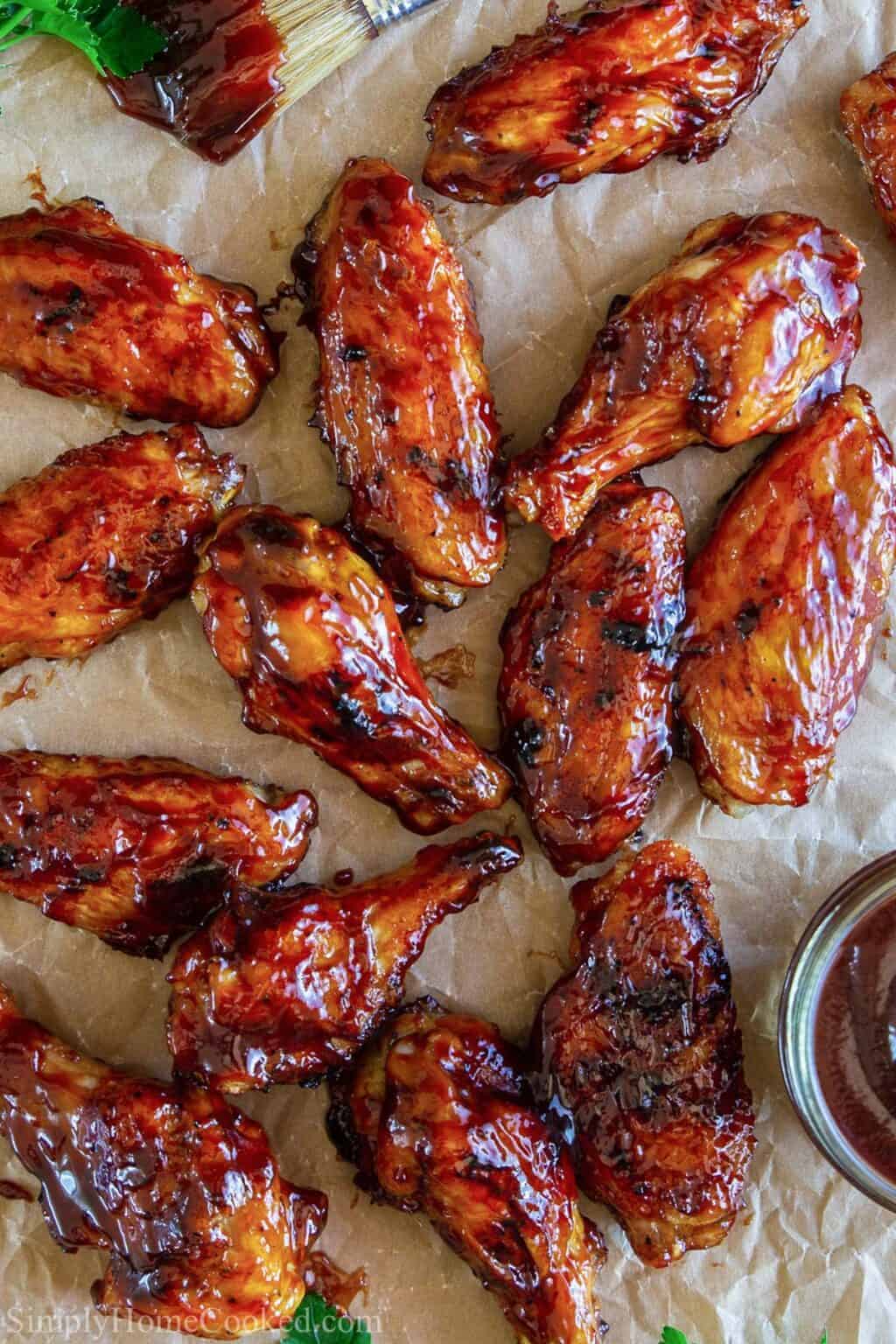 Barbecue sauce coated chicken wings on brown parchment paper. 