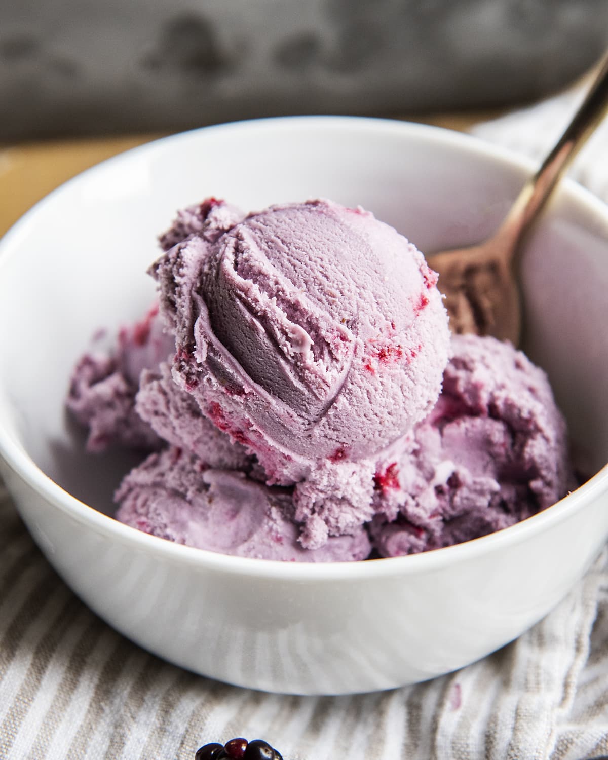 A close up of a bowl of scoops of blackberry ice cream.