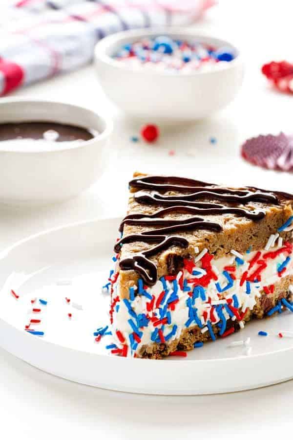 A slice of a chocolate chip ice cream cake topped with patriotic sprinkles. 