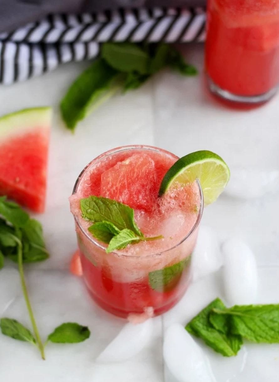 A pink watermelon drink topped with fresh mint and a lime slice.