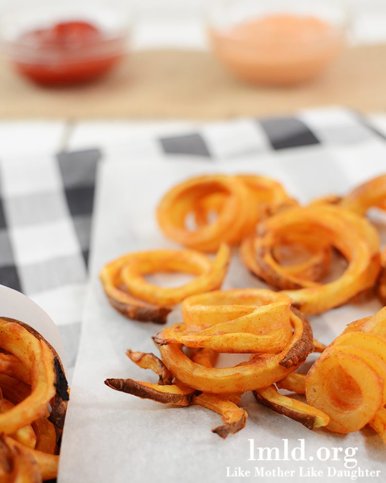 Close up view of oven baked curly fries on a napkin.