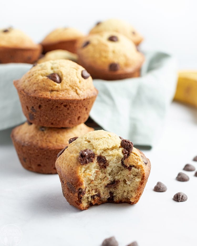 Close up image of multiple banana chocolate chip muffins with chips around them.