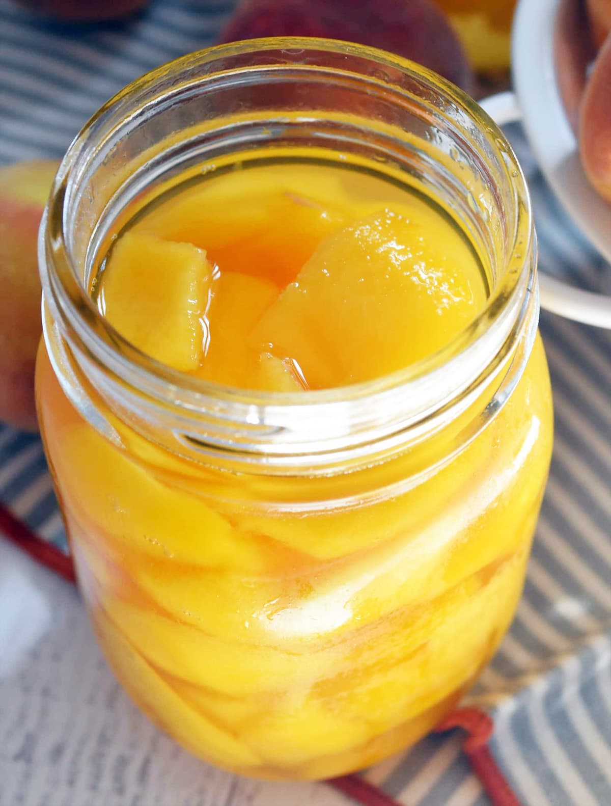One open pint jar of yellow peaches