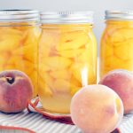 Three jars of bottled peaches with lids on them.