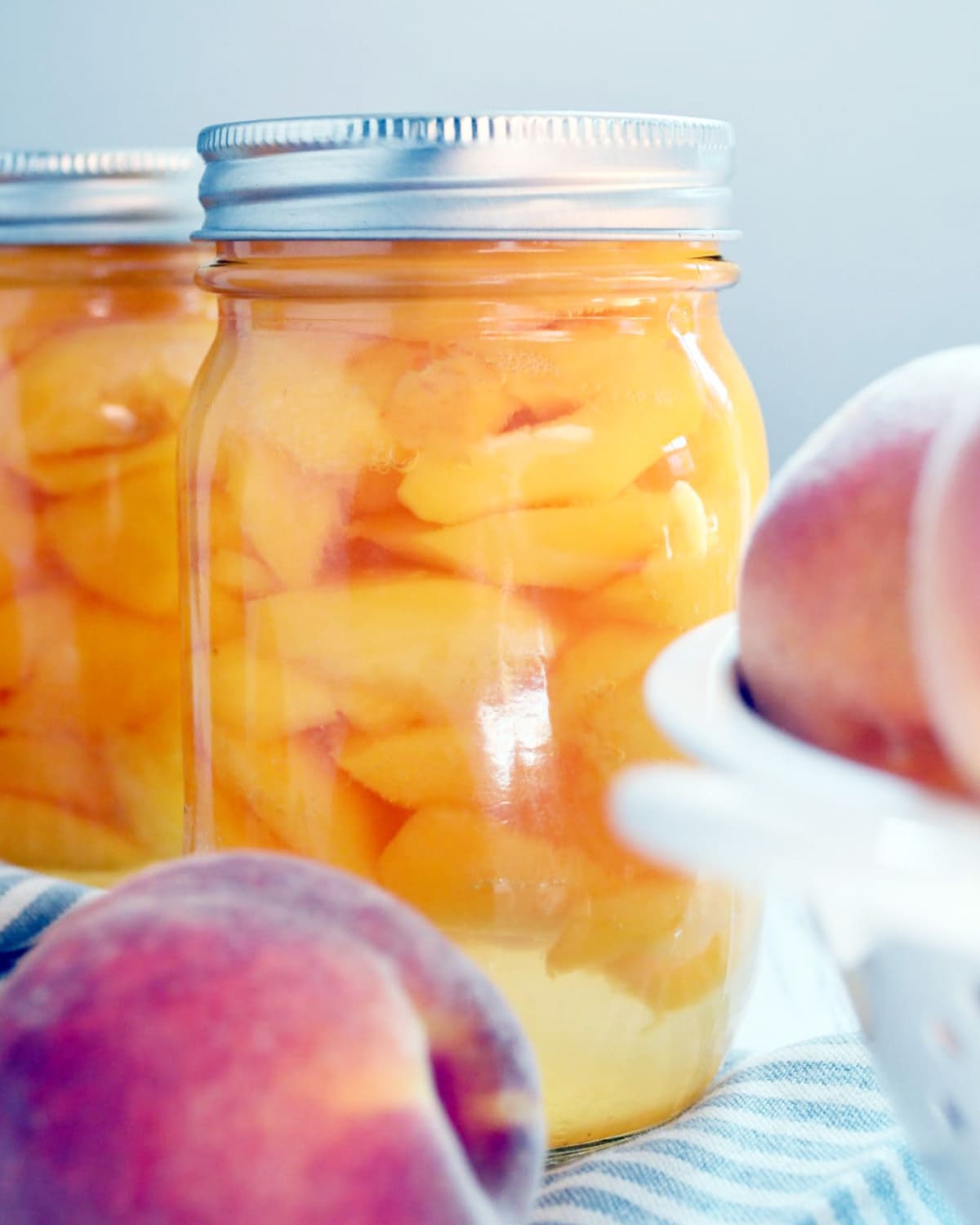 A jar of bottled peaches with simple syrup in there too, with the silver lid on top.