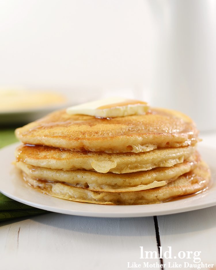 Side view of a stack of pancakes on a white plate.