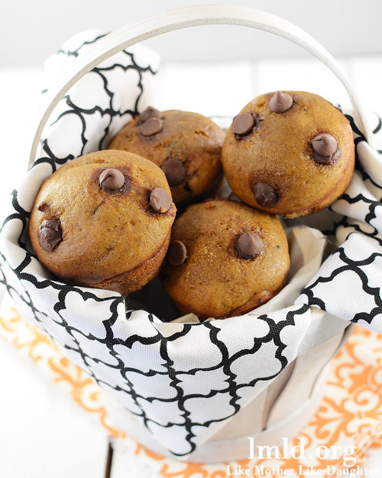 A basket full of pumpkin muffins with chocolate chips. 