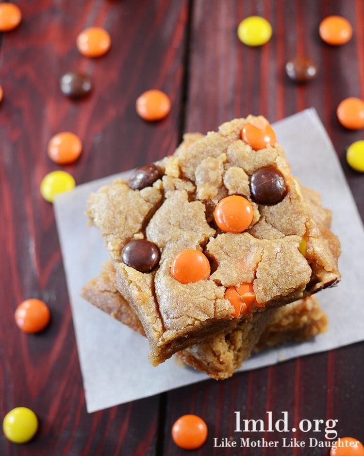 Top view of reeses pieces peanut butter blondies on a white parchment.