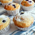 Blueberry coconut orange muffins on a white and blue cloth.
