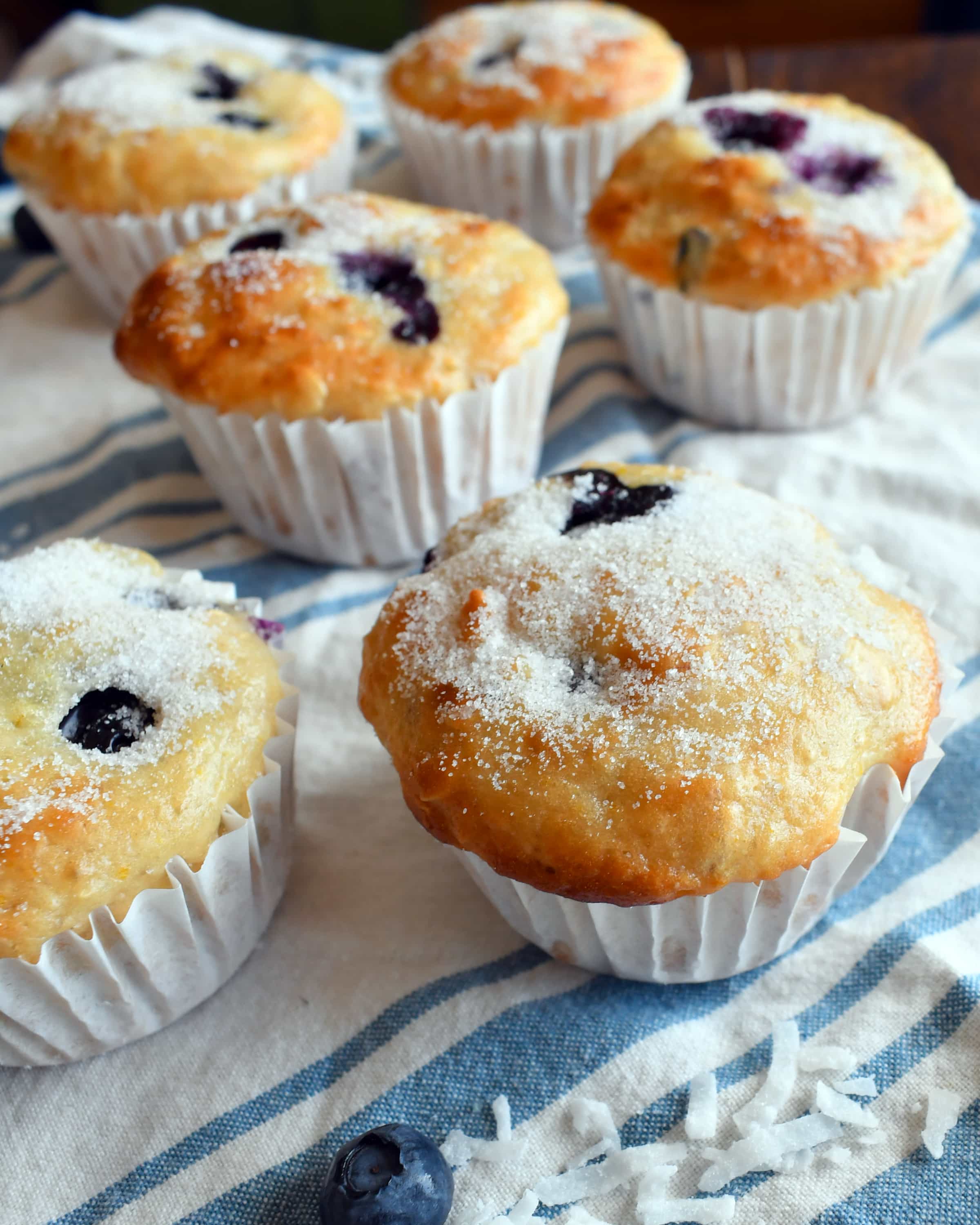 Blueberry coconut orange muffins on a white and blue cloth.